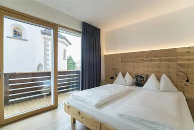 a bedroom with a bed and a large window at Apartments Jalve in Ortisei