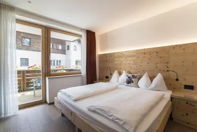 a bedroom with a large bed and a large window at Apartments Jalve in Ortisei