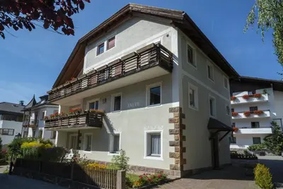 a white building with a gambrel roof at Apartments Jalve in Ortisei