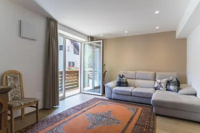 a living room with a couch and a large window at Apartments Jalve in Ortisei