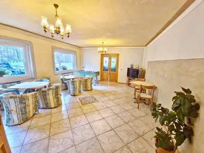 a living room with tables and chairs and a tv at Villa Flora by AMA Val di Fassa in Canazei
