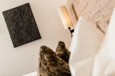 a lamp sitting on a bed next to a wall at ArtHotel Anterleghes - Gardenahotels in Selva di Val Gardena