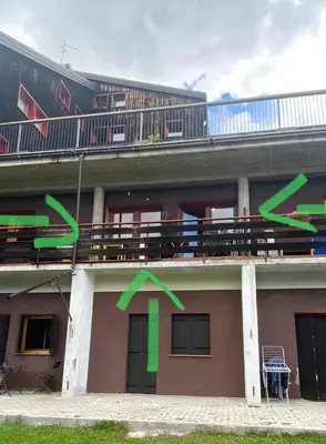 a building with a balcony with green arrows on it at Casa Focobon - presso Sussy residence in Falcade