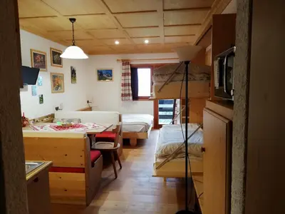 a room with a bedroom and a bed and a table at Casa Focobon - presso Sussy residence in Falcade