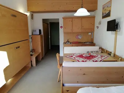 a room with a bed and a table in it at Casa Focobon - presso Sussy residence in Falcade