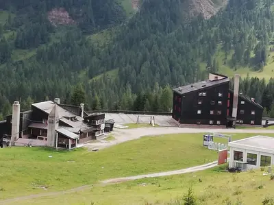 a large building in a field next to a mountain at Casa Focobon - presso Sussy residence in Falcade