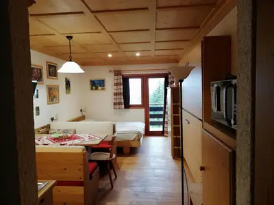 a small room with a bed and a table in a room at Casa Focobon - presso Sussy residence in Falcade