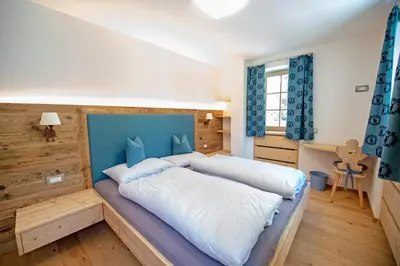 a bedroom with a large bed with a blue headboard at Apartments Alpen Domus in Selva di Val Gardena