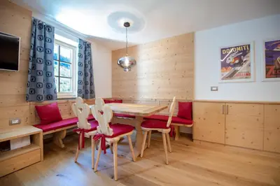 a dining room with a wooden table and red chairs at Apartments Alpen Domus in Selva di Val Gardena