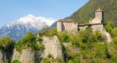 a castle on top of a hill with a mountain at B&B Hotel Mair am Turm in Tirolo