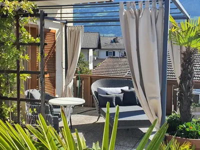 a patio with a chair and a table and curtains at B&B Hotel Mair am Turm in Tirolo