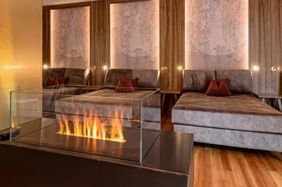 a living room with a fireplace and two beds at Romantik Hotel Oberwirt in Marlengo