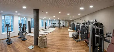 a gym with a row of treadmills and machines at Romantik Hotel Oberwirt in Marlengo