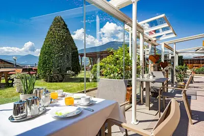 a restaurant with tables and chairs on a patio at Hotel Stefanie in Tirolo