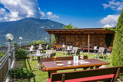 a patio with tables and chairs and a building at Hotel Stefanie in Tirolo