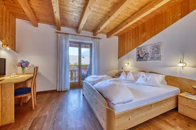 a bedroom with a bed and a desk and a window at Hotel Stefanie in Tirolo