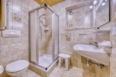 a bathroom with a shower and a toilet and a sink at Hotel Stefanie in Tirolo