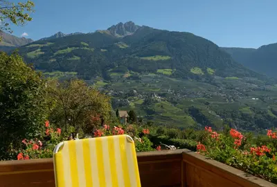 a yellow chair sitting on a balcony overlooking a valley at Hotel Stefanie in Tirolo