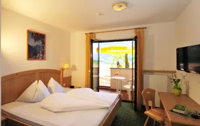 a hotel room with a bed and a desk and a table at Hotel Weger in Tirolo