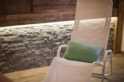 a white rocking chair in front of a brick wall at Hotel Weger in Tirolo