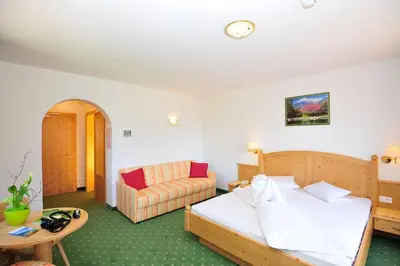 a hotel room with a bed and a couch at Hotel Weger in Tirolo