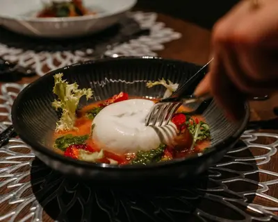 a person is eating a bowl of food with a fork at Terentnerhof 4*S active & lifestyle hotel in Terento