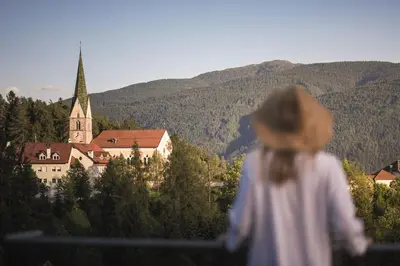 a girl standing on a balcony looking at a church at Terentnerhof 4*S active & lifestyle hotel in Terento