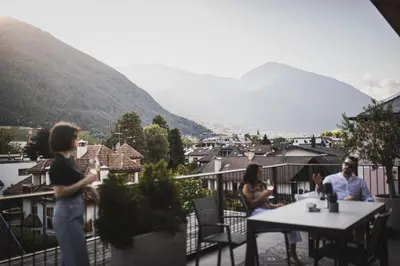 a group of people sitting at tables on a balcony at Residence Nives in Bressanone