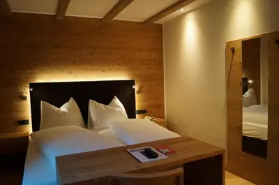 a bedroom with a large white bed with a wooden wall at Hotel Laurin in Tires