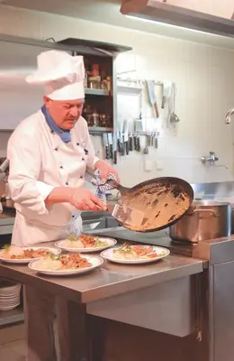 a chef preparing plates of food in a kitchen at Hotel Laurin in Tires