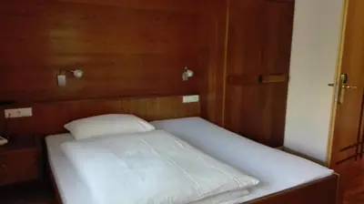 a small bed in a room with wooden walls at Pensione Valbona in Corvara in Badia