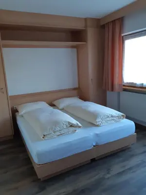 two beds in a room with a window at Pensione Valbona in Corvara in Badia