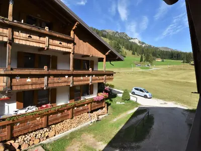 a log house with mountains in the background at Apartment Cesa Galadriel-2 by Interhome in Penia