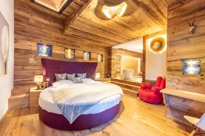 a bedroom with a large bed in a room with wooden walls at Alpine Refuge Villa Adler in San Vigilio Di Marebbe