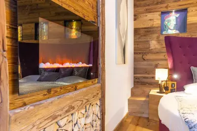 a bedroom with a fireplace in a wooden wall at Alpine Refuge Villa Adler in San Vigilio Di Marebbe
