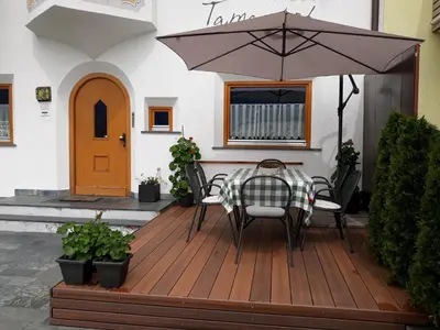 a table and chairs on a wooden deck with an umbrella at App. Tamanhof in San Giorgio