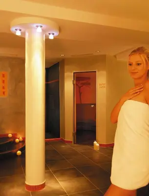 a woman in a white dress standing next to a column at Hotel Plunger in Castelrotto