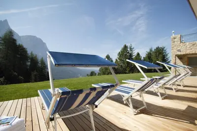 a group of chairs sitting on a wooden deck at Hotel Plunger in Castelrotto