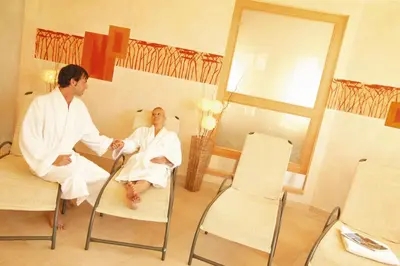 a man and a woman sitting on chairs in a room at Hotel Plunger in Castelrotto