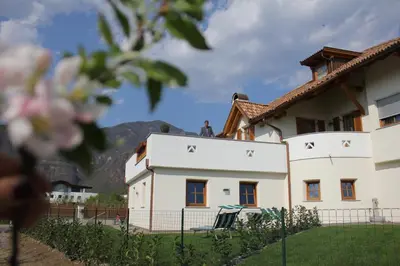 a white house with mountains in the background at Apartments Klotz in Bolzano