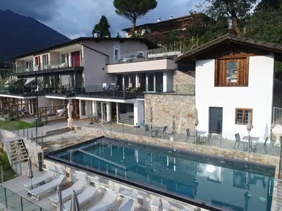 a villa with a swimming pool in front of a house at La Pergola PanoramaSuites in Tirolo