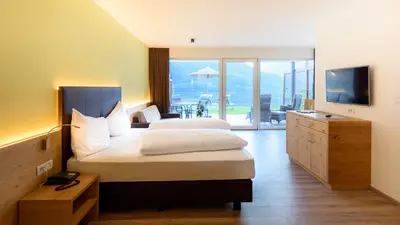 a hotel room with two beds and a television at La Pergola PanoramaSuites in Tirolo