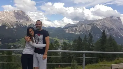 a man and a woman standing in front of a mountain at Hotel Regina in Cortina dʼAmpezzo