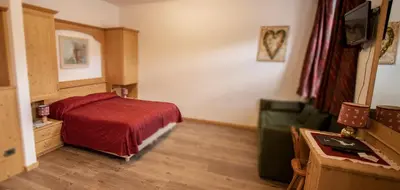 a bedroom with a red bed and a couch at Hotel Regina in Cortina dʼAmpezzo