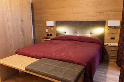 a bedroom with a bed with a red comforter at Hotel Regina in Cortina dʼAmpezzo