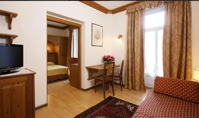 a living room with a television and a table in a room at Hotel Regina in Cortina dʼAmpezzo