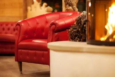 a red leather chair sitting next to a table at Hotel Antermoia in Antermoia