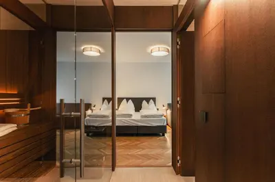 a bedroom with a bed and a glass door leading into a room at Aquila Dolomites Residence in Ortisei