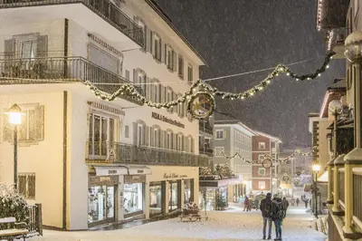 people walking down a street in the snow at Aquila Dolomites Residence in Ortisei