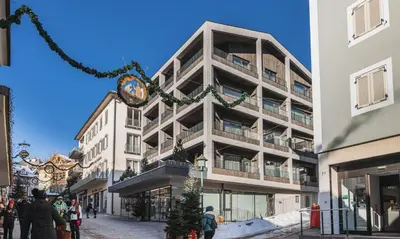 a tall building with a clock hanging from it at Aquila Dolomites Residence in Ortisei